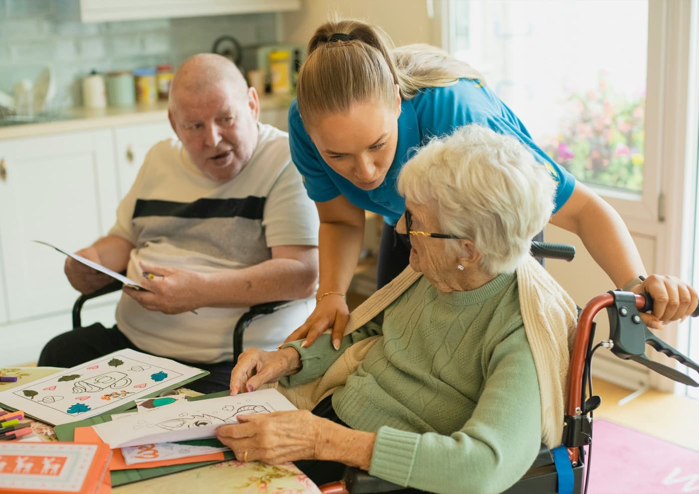 A caregiver spending time with an older couple at their kitchen table
